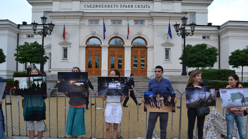 Группа протестующих с фотографиями оккупации парка Гези стоит перед зданием болгарского парламента во время протестов 2013 г.