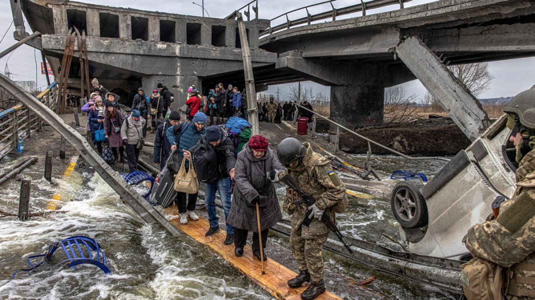Украински военни помагат на бягащи жители на град Ирпин, Киевска област, да прекосят реката под разрушен мост. 7 март, 2022 г. Снимка: ЕПА/БГНЕС