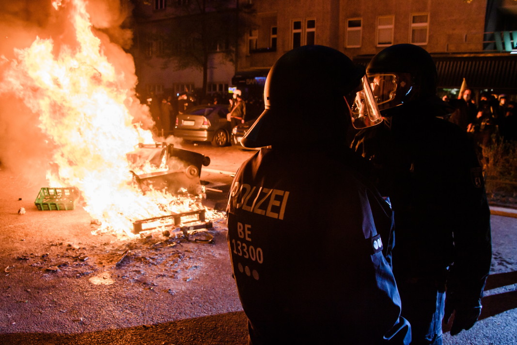 Полицейска част  за борба с безредиците заема позиция до горяща барикада по време на протест на 1 май в Берлин.