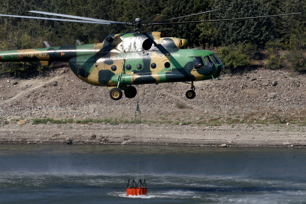Армейски противопожарен хеликоптер пълни контейнер с вода близо до района, засегнат от горски пожари до село Неманджици, Северна Македония, 30 юли 2024 г.; ЕПА/БГНЕС