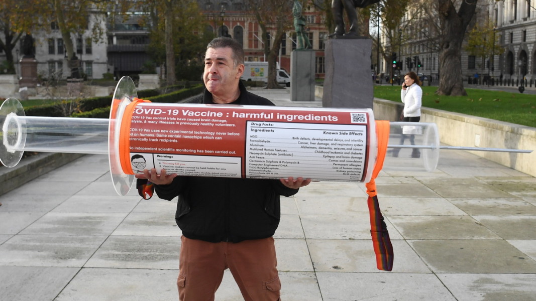 Мъж държи уголемен макет на спринцовка с изброени вредни съставки във ваксините. Германия, есента на 2020 г. Снимка: ЕПА/БГНЕС