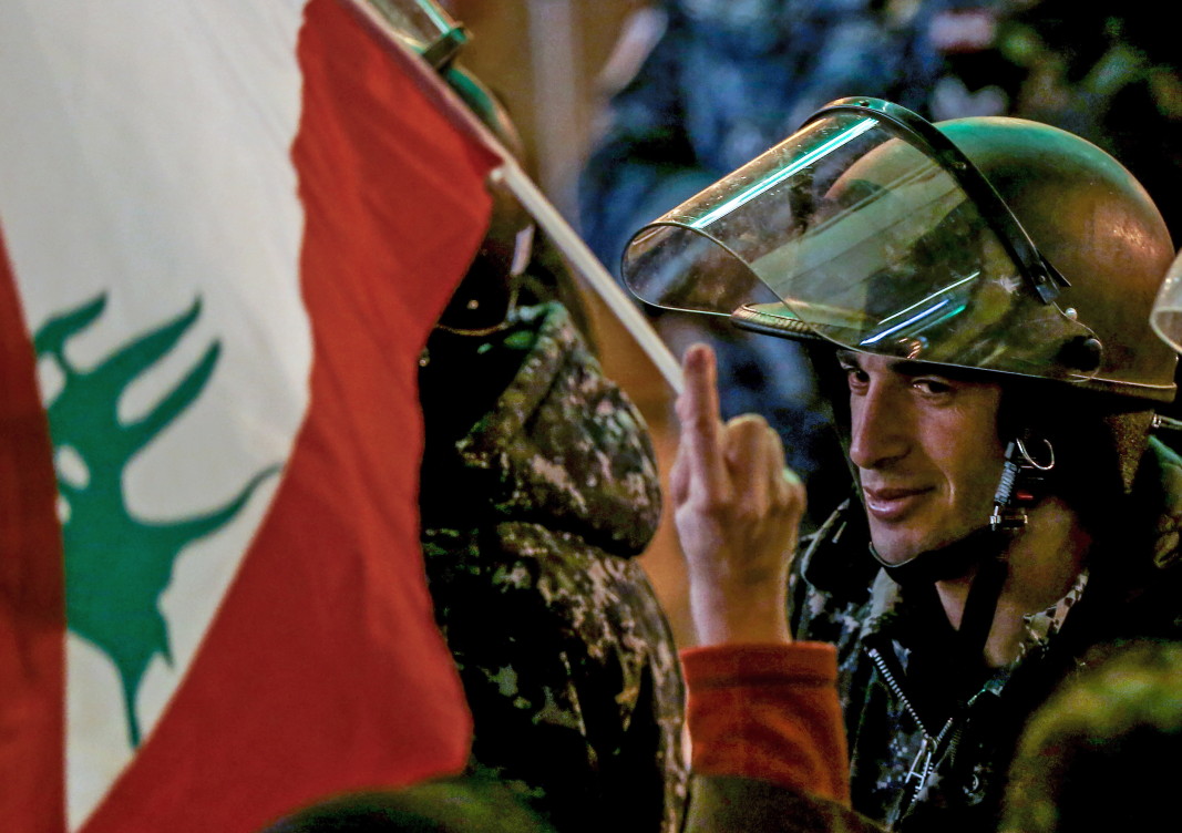Протестираща ливанка развява флага на страната пред строго охраняваната сграда на парламента.