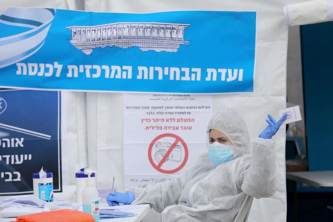 Член на избирателна комисия в Ерусалим с пълно защитно облекло, препястващо разпространение на вируси