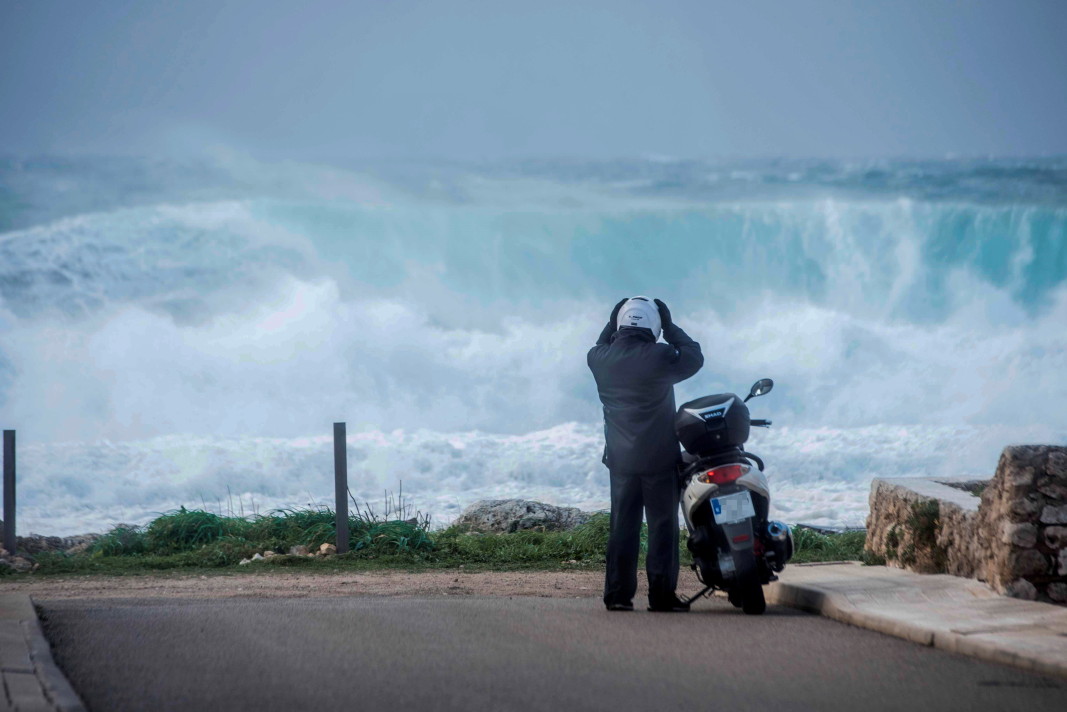 Мотоциклетист е спрял, за да наблюдава вълните, които се разбиват на плаж в Менорка, Испания, 28 декември 2020 г.