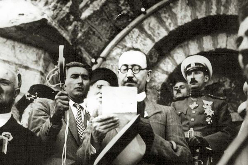 Kimon Gueorguiev ante el micrófono de Radio Sofía leyendo su discurso durante la inauguración del monumento Shipka en 1934. El zar Boris lo mira y escucha con un evidente desprecio