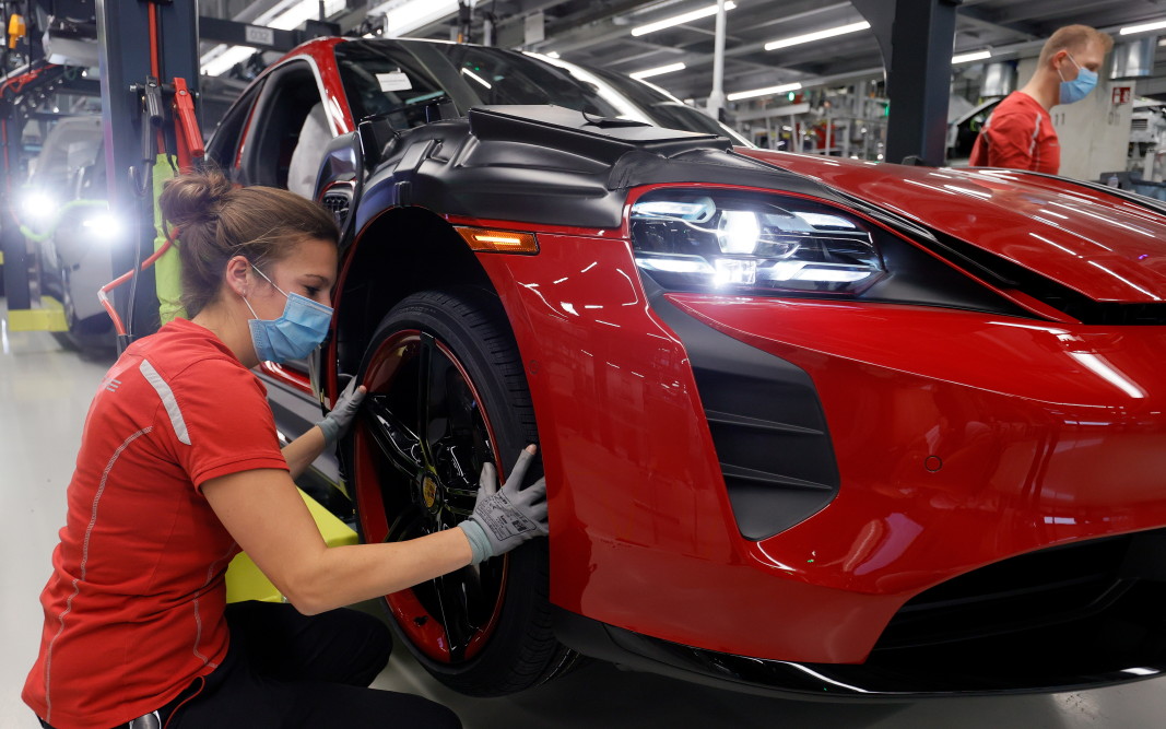 Работници, носещи защитни маски и ръкавици, на производствената линия на спортните автомобили Taycan на Porsche в Щутгарт, Германия, май 2020 г.