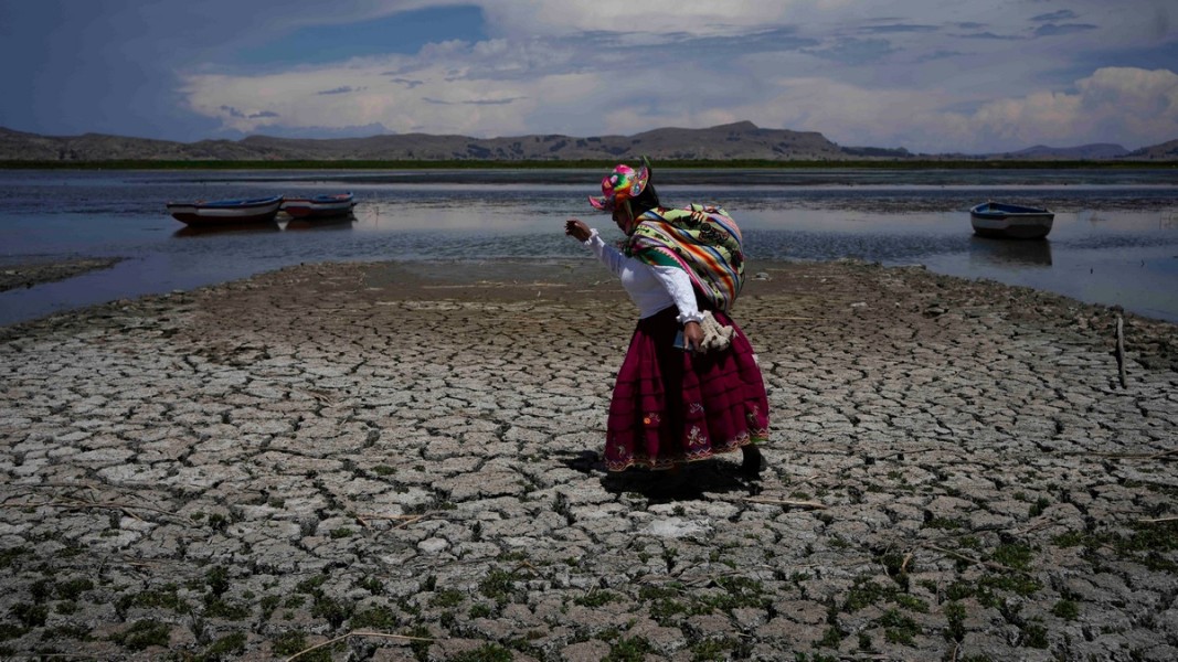 Жена преминава през сух участък от езерото Титикака в Перу, след като гореща зимна вълна е понижила водните нива.