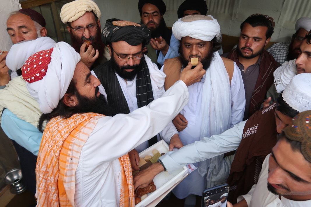 Членове на религиозна организация в Кета, Пакистан, се черпят със сладки по повод военните победи на талибаните, 13 август 2021 г./ЕПА/БГНЕС