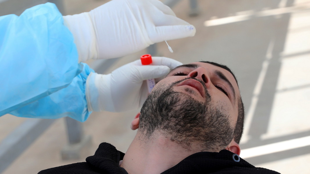 Здравен служител взема проба за Covid-19 на работник в Палестинската автономия. Снимка: ЕПА/БГНЕС