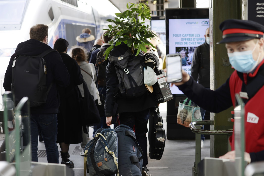 В часовете до влизането в сила на новите ограничения парижани се редиха на опашки пред магазините за дрехи и за домашни мебели, очаквайки затварянето им, а мнозина напуснаха града. Пътник, който се качва на влак, за да отпътува от Париж, носи и стайното си растение, за да не го оставя без поливане по време на новия локдаун, който обхваща и района на столицата – Gare de Lyon, Париж, 19 март 2021 г.
