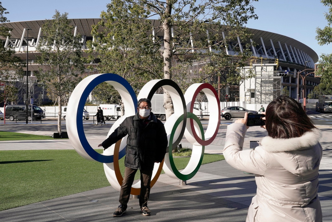 Турист се снима пред олимпийските кръгове в Токио.