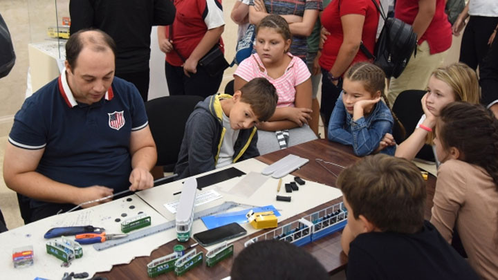 Деца и възрастни гледат как се правят макети на трамваи