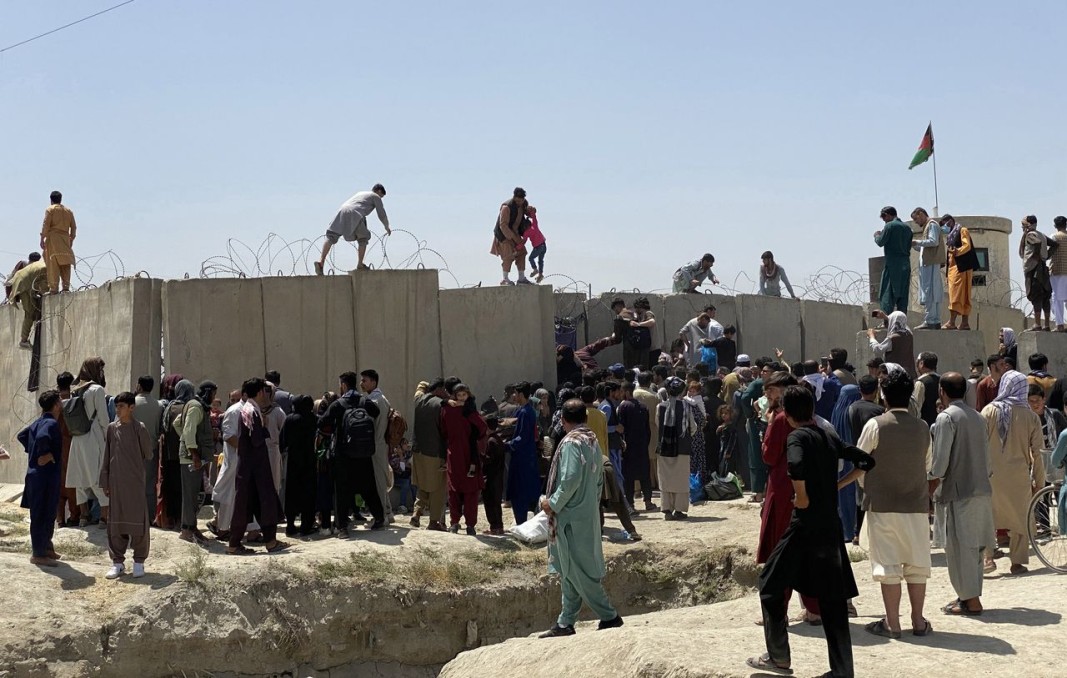 Афганистанци се опитват да се доберат до самолет, с който да избягат от талибаните, прескачайки оградата на летището на Кабул. Снимка ЕПА/БГНЕС