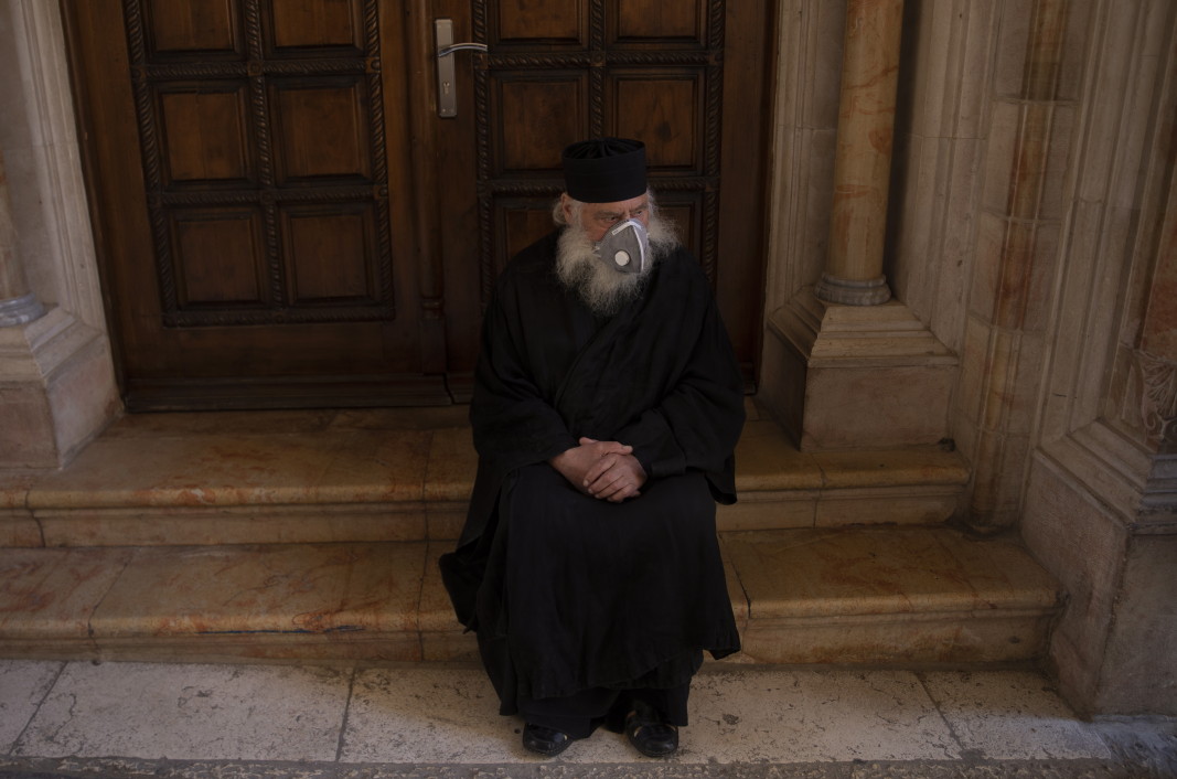 Гръцки православен свещеник, носещ маска за лице, чака слизането на Благодатния огън на Божи гроб, в стария град на Йерусалим, 18 април 2020 г.