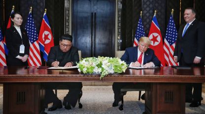 Доналд Тръмп и Ким Чен-ун подписват съвместния документ след срещата си в Сингапур.