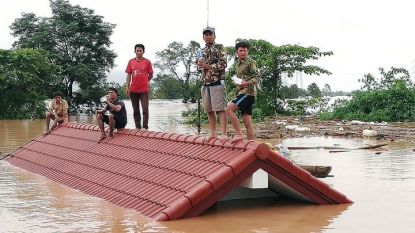 Лаоски селяни стоят на покрива на къща след евакуацията им заради наводнение, предизвикано от рухване на язовирна стена в югоизточната част на страната.