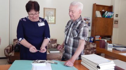 Началникът на отдела на Държавния архив във Видин Светлана Кръстева показва на Жан Гологанов снимки, дарени от неговия прадядо 