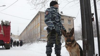 Полицай с куче стои пред атакуваното училище №127 в Перм, Русия.