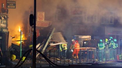 Служители на спешни служби на мястото на експлозията и последвалия пожар късно в неделя в сграда в Лестър, Англия.