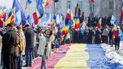 Момиче си прави селфи на фона на огромно румънско знаме по време на манифестация на централния площад в столицата на Молдова – Кишинев