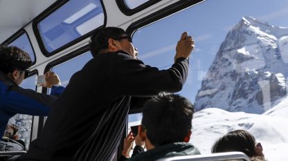 Туристи правят снимки, возейки се в зъбчатата железница Юнгфраубан в Швейцария.