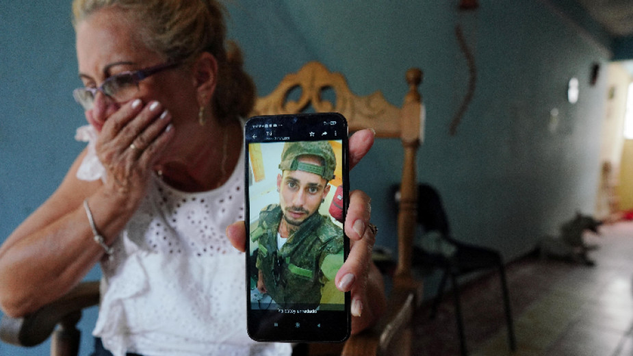 Кубинка показва снимка на сина си във военна униформа, Хавана, септември 2023 г.