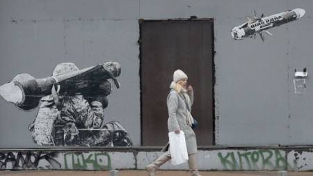 Жена минава край графит в Киев, изобразяващ как украински войник изстрелва противотанкова ракета с надпис 