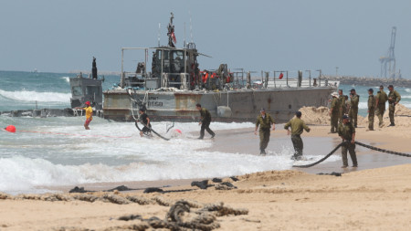 Американски и израелски войници оценяват ситуацията на американски военен кораб в град Ашдод, Израел, на 26 май 2024 г. 
Според САЩ армейските кораби, превозващи част от дока, предназначен за предоставяне на хуманитарна помощ на Ивицата Газа, са изхвърлени на брега в Ашдод поради метеорологичните условия. 