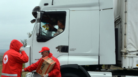 Доброволци на БЧК раздават бутилирана вода и кроасани на бедстващите шофьори на камиони край ГКПП 
