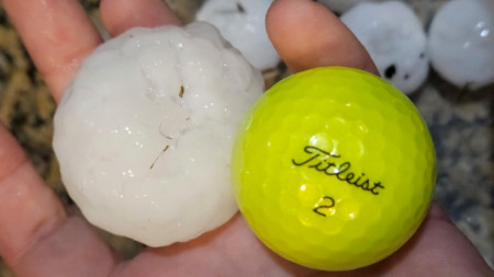 Жител на Канзас държи в шепата си късове от падналата вчера градушка и за сравнение е поставил до тях топка за голф. 