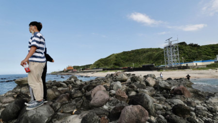 Хора на крайбрежието в Тайпе, Тайван, гледат в посоката на ученията на Китай