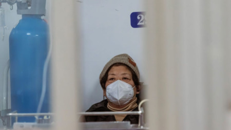 Жена получава интравенозна терапия, докато седи в коридора на болница в Шанхай, 13 януари 2023 г. 