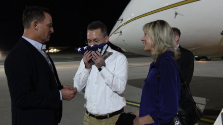 Андрю Брънсън целува знамето на САЩ на летището във ВВС базата Рамщайн, Германия, където бе посрещнат от US посланика в Берлин Ричард Гренел (вляво)