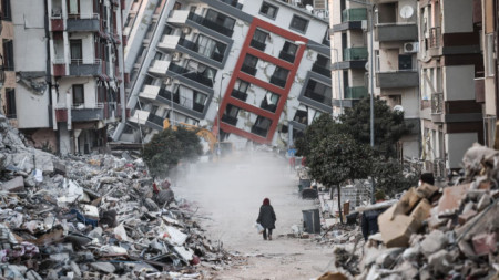 Жена върви между развалините на срутени от земетресението сгради в Хатай, Турция, 17 февруари 2023 г.