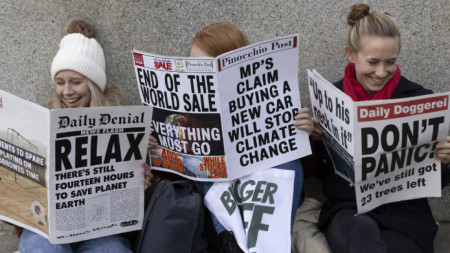 Протестиращи в Глазгоу, където продължава климатичната среща на върха на ООН, иронизират световните лидери, държейки фиктивни вестници с успокояващи заглавия.