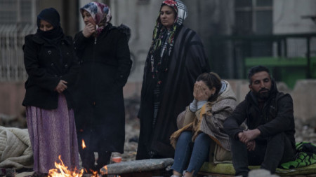 Хора се топлят на огън до разрушена от земетресението сграда в Диарбекир, Турция, 9 февруари 2023 г.