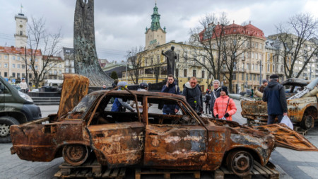 Минувачи разглеждат унищожени автомобили, пренесени от доброволци от фронтовата линия до Бахмут. Лвов, януари 2023 г.