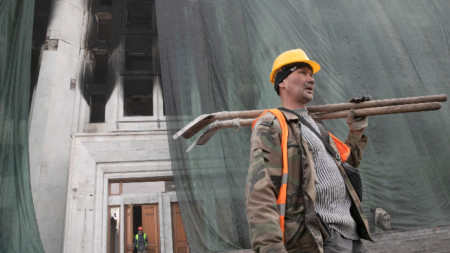 Работник пред изгорялата сграда на кметството в Алмати, Казахстан, 13 януари 2022 г.