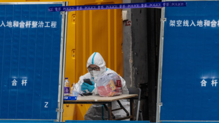 Мъж в защитно облекло охранява комплекс за карантина в Шанхай, където са регистрирани над 80% от новите случаи в Китай