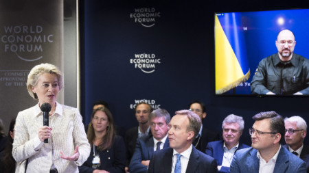 Председателят на ЕК Урсула фон дер Лайен говори по време на видеосреща на Световния икономически форум (СИФ, WEF) в Давос, Швейцария, 25 май 2022 г. На преден план седнали: Председателят на СИФ Бьорг Бренде и външният министър на Украйна Дмитро Кулеба. На видеоекрана е премиерът на Украйна Денис Шмигал. 