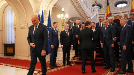 Румънският премиер Илие Боложан си тръгва, докато румънският президент Никушор Дан, вдясно, се ръкува с министрите от новото правителство след церемонията по полагане на клетва в президентския дворец 