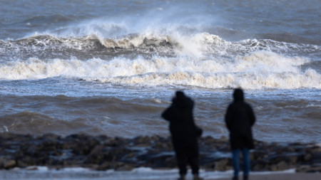 Хората наблюдават вълните от плажа в Ню Брайтън, Великобритания, 22 януари 2024 г.