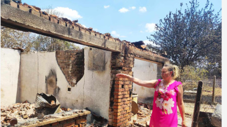 Жена показва останките от изгорялата ѝ къща.
