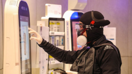 Мъж в защитно облекло проверява автомат за лекарства в супермаркет в град Ухан, провинция Хубей, където за първи път бе регистриран новия корона вирус.