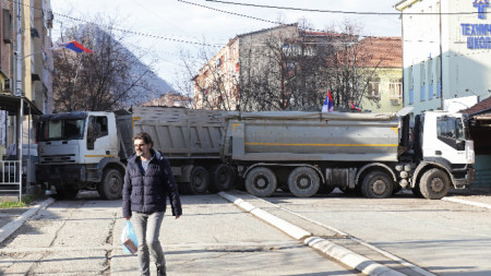 Жител минава покрай камиони, блокиращи пътя в северната част на Митровица, Косово, 29 декември 2022 г. 