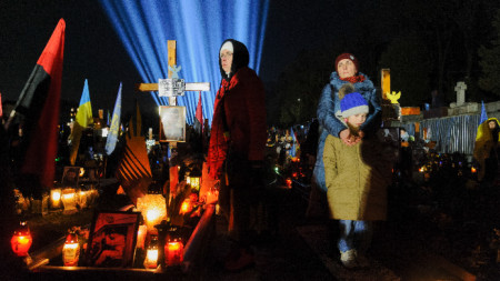 Близки на загинали украински войници се молят на фона на символични 