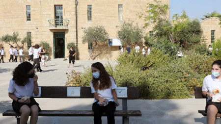 Деца седят с маски на разстояние едни от други на пейка в училищен двор в Никозия - 7 септември 2021 г.
