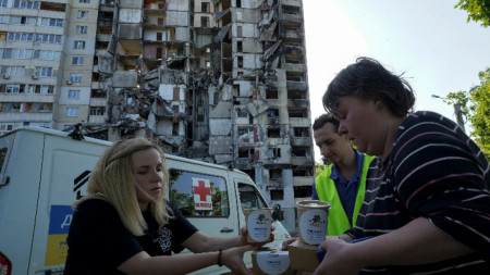 Жители на Харков получават помощи пред пострадалия си от ракетен удар блок, 2 юни 2023 г.