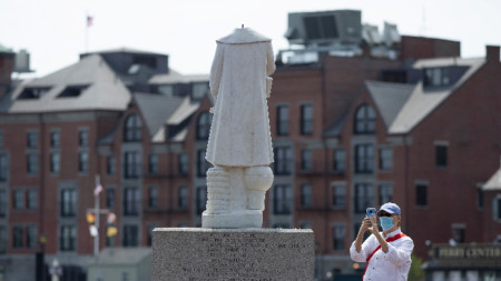 Минувач фотографира обезглавената статуя на Христофор Колумб в парк на Бостън, Масачузетс, САЩ, 10 юни 2020 г. 