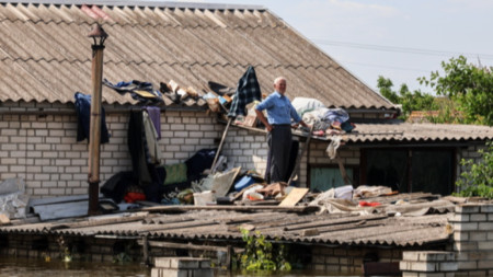Местен жител на покрива на къщата си в наводнения район на Херсон, Украйна, 09 юни 2023 г. 